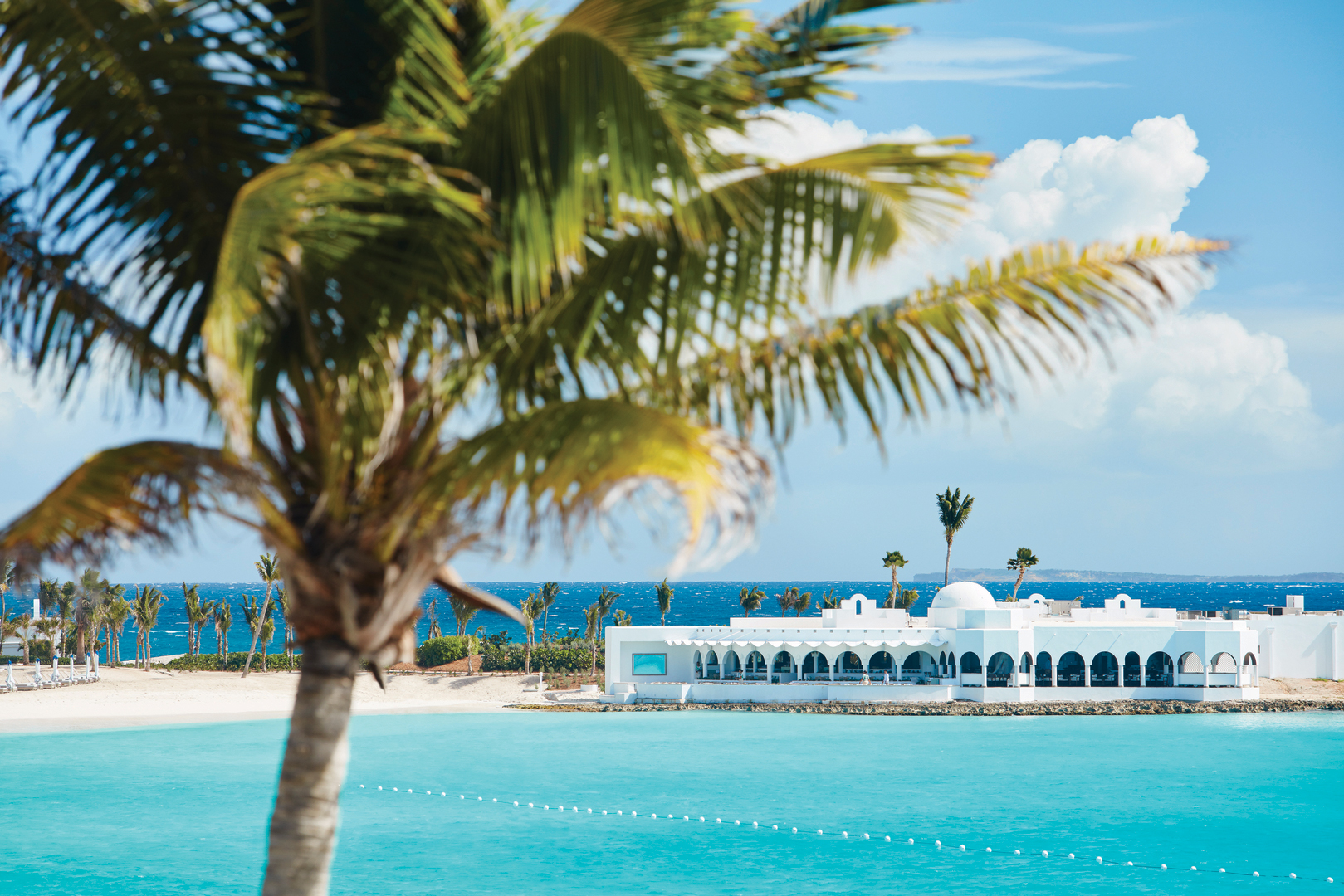 Belmond Cap Juluca luxury resort in Anguilla, framed by palm trees and turquoise Caribbean waters