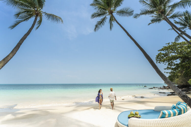 Couple walking on a tropical beach in Thailand – luxury vacation under palm trees