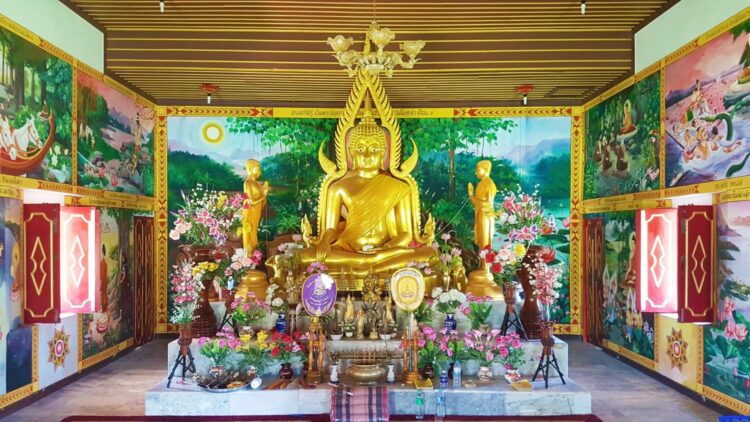 Golden Buddha shrine in Thailand with vibrant mural art and offerings