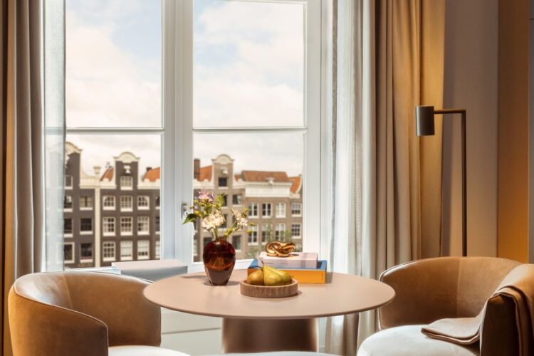 Cozy seating area in front of a window with canal houses in view