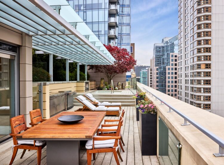 Spacious city-view terrace with dining table, loungers, and modern skyscrapers in the background