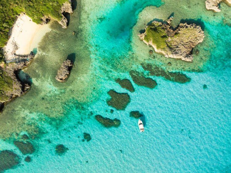Aerial view of turquoise waters and coral formations near a white sand beach
