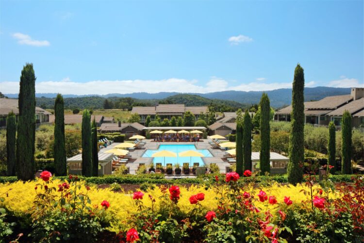 Resort pool with yellow umbrellas surrounded by landscaped gardens and hills