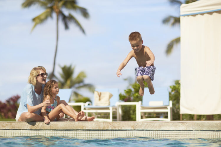 Young boy jumping into the pool at Four Seasons Maui during a luxury family holiday in Hawaii