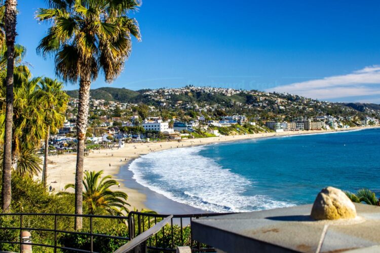 Laguna Beach California coastline with palm trees and hillside town — luxury beach family vacation in Southern California