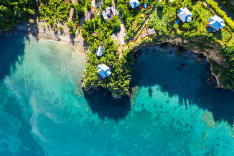 Aerial view of Zabuco Villas at Secret Bay, Dominica, showing cliffside luxury villas and lush tropical vegetation overlooking turquoise bays and secluded sandy beaches.