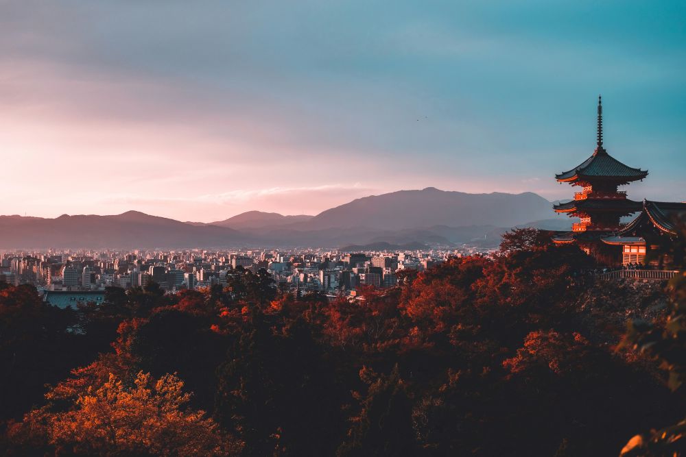 Kyoto skyline at sunset with a traditional pagoda overlooking the city and distant mountains during autumn