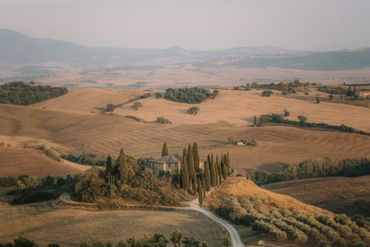 Val d'Orcia in Italy in September — stone farmhouse and cypress trees